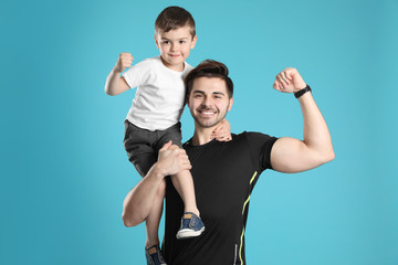 Portrait of sporty dad and his son on color background