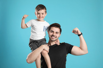 Portrait of sporty dad and his son on color background