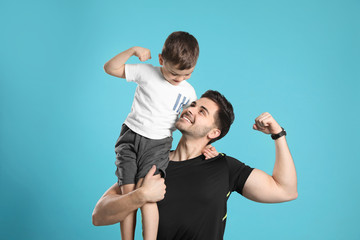 Portrait of sporty dad and his son on color background