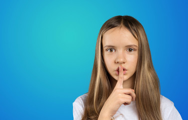 Portrait of girl child keeping finger on her lips and asking to keep quiet