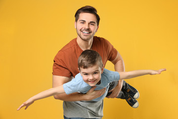 Portrait of dad playing with his son on color background