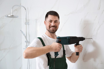 Handyman working with drill in bathroom. Professional construction tools