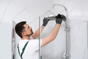 Professional handyman working in shower booth indoors - obrazy, fototapety, plakaty