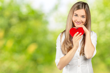 Girl with happy romantic face holds soft toy heart with hands