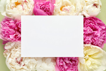 Fresh peonies and empty card on color background, flat lay with space for text