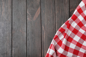 Fototapeta premium Checkered picnic blanket on wooden background, top view. Space for text