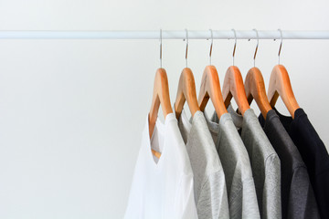 close up collection of black, gray and white color (monochrome) hanging on wooden clothes hanger in closet or clothing rack over white background, copy space