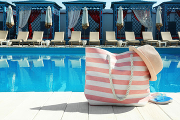Beach accessories on wooden deck near swimming pool. Space for text