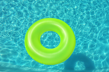 Bright inflatable ring floating in swimming pool on sunny day, above view