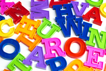 Heap of plastic colored alphabet letters close up.
