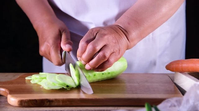 Woman slicing Cucumber on the cutting board - close up