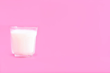 Glass of cool milk on pink background. Heathy beverage concept.