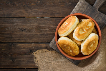 Pies in a ceramic bowl on a wooden background. National dish. Rustic style