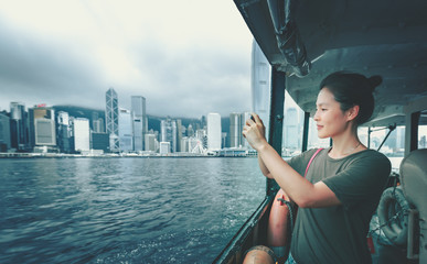 Fototapeta premium Woman using smartphone on ferry which just passing the famous Victoria Harbor in Hong Kong 
