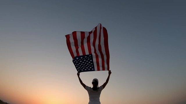 US flag - woman athlete showing american flag. Beautiful cheering happy young multicultural girl joyful excited.