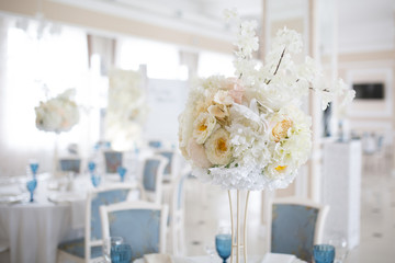 Festive concept of white wedding. Flower arrangement of artificial bouquet on the table.