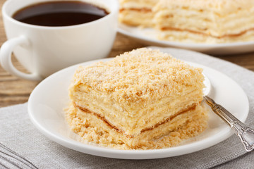 Piece of cake with cup of coffee on wooden table.
