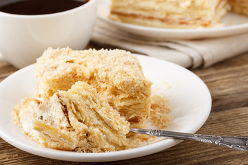 Piece of cake with cup of coffee on wooden table.