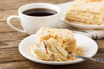 Piece of cake with cup of coffee on wooden table.