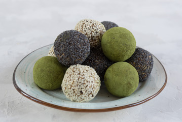 Vegetarian food. Handmade energy balls with poppy, sesame and matcha tea in plate on a white background. Close up. Selective focus