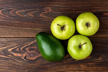 Avocado and green apple on dark wooden background.