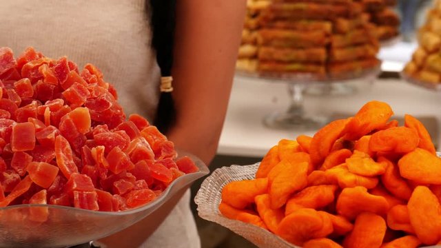Dried fruits on a market in the Spanish La Zenia near Torrevieja. The sweets are offered for sale by the young saleswoman in glass bowl.