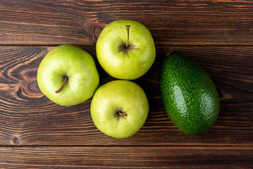 Avocado and green apple on dark wooden background.