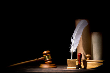 Wooden judge gavel hammer, old inkstand with feather quill, blotter, seal near scrolls against...