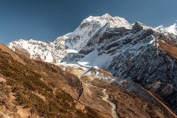Fototapeta na wymiar Huge valley with river on Manaslu circuit with view of snow covered Mount Manaslu 8 156 meters. Himalayas, sunny day at Manaslu Glacier in Gorkha District in northern-central Nepal. 