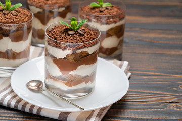 Classic tiramisu dessert in a glass on wooden background