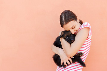 Beautiful girl hugging tight her cute small puppy