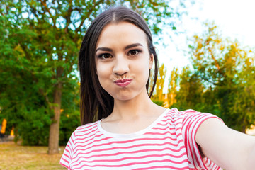 Pretty smiling girl making selfie, long-haired brunette in white clothes, closeup