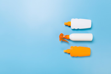 flat lay concept of summer travel vacation. Sunscreen bottle mock up on blue background top view with copy space