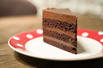 Dark chocolate cake with red white plate on wood table