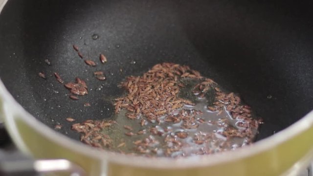 Cooking video of seeds in oll in a pan kept on stove. Shot in natural soft lighting