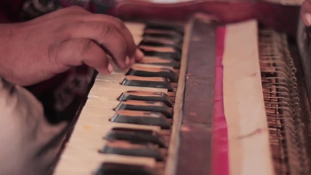A man playing an old Indian instrument harmonium and tabla.