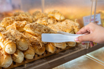 Close up of hand picking pork floss bread with clamp