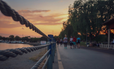 Scenic defocus sunset view of pedestrians and cyclists walking and cycling on the Caddebostan promenade in İstanbul,Turkey. An abstract sun set and cloudy sky on the background. Road fence.
