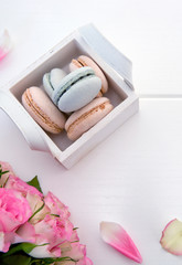 Pink roses and macaron cookies in the basket on white background.