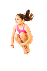 Little caucasian female 8 years old girl in pink swimmwear jumping on white background.