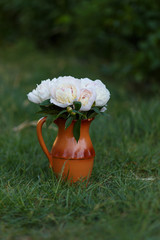 a jug of flowers on green grass