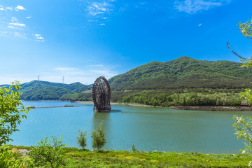 Fototapeta na wymiar Large wooden waterwheel and blue water, Xijiao National Forest Park, Dalian, China