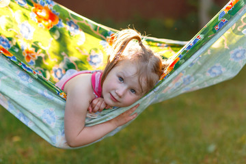 A little girl having fun in the hammock in summer at the sunset