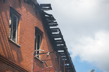 Smoldering remains of a ghetto house with a fireman spraying water