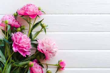 Pink peony flowers on white wooden table. womans day or wedding background.