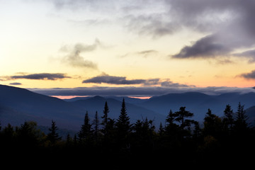 Wooded mountains and pink clouds on the peaks at sunset. White Mountain National Park. USA. New Hamshire.