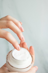 Young woman cares about her hands, applying cream on them.Close up shot of hands and whire cream.Top view.