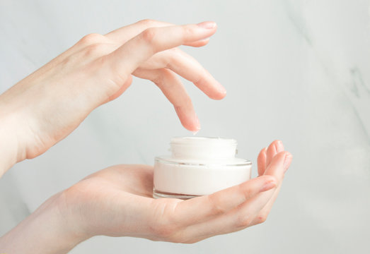 Beauty woman holding a glass jar of skin cream. Skin care concept. Woman taking care of her dry body. Moisturizing cream in female hands . Beauty treatment. Copy space.