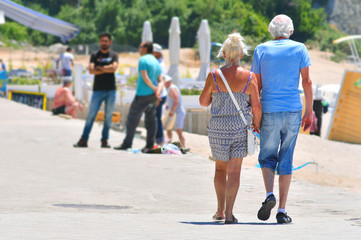 Elderly couple walking along the promenade, holding each other's hands