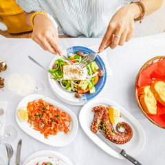Close-up of a woman eating delicious seafood - shrimp and octopus grilled and vegetable salad. The concept of Mediterranean cuisine and healthy food
